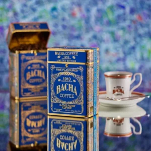 青と金の限定缶「I LOVE PARIS」ブレンドとバシャコーヒーのロゴ入りカップ。芸術的な背景に映える豪華な演出。