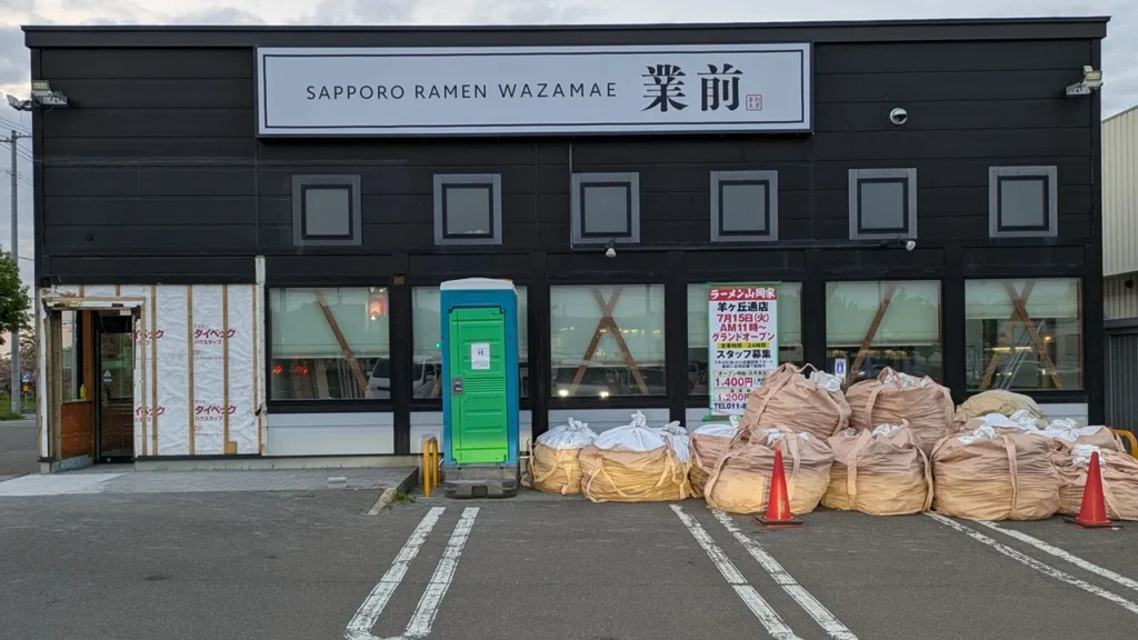 旧店名「業前」の看板が残る建物に山岡家のオープン日の看板が映る改装中の様子（2025年5月21日撮影）